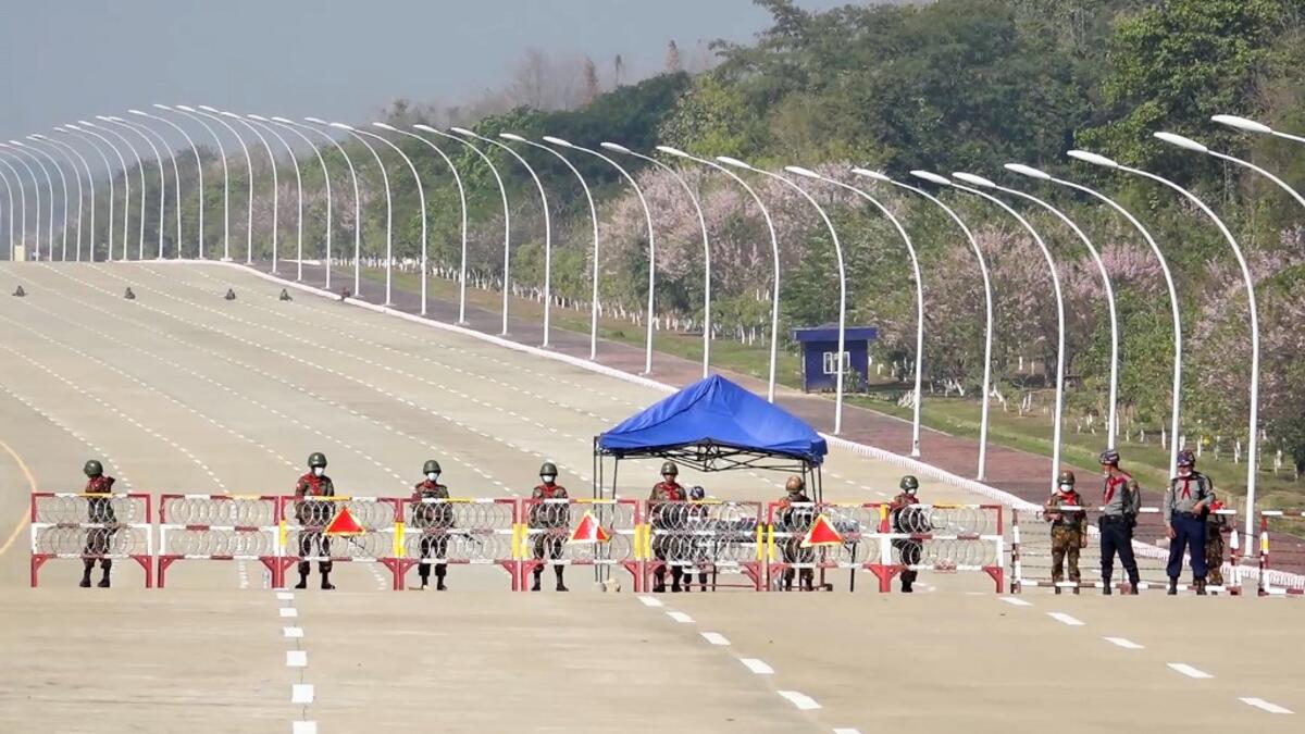 Soldiers stand guard on a blockaded road to Myanmar's parliament in Naypyidaw on February 1, 2021, after the military detained the country's de facto leader Aung San Suu Kyi and the country's president in a coup. STR / AFP