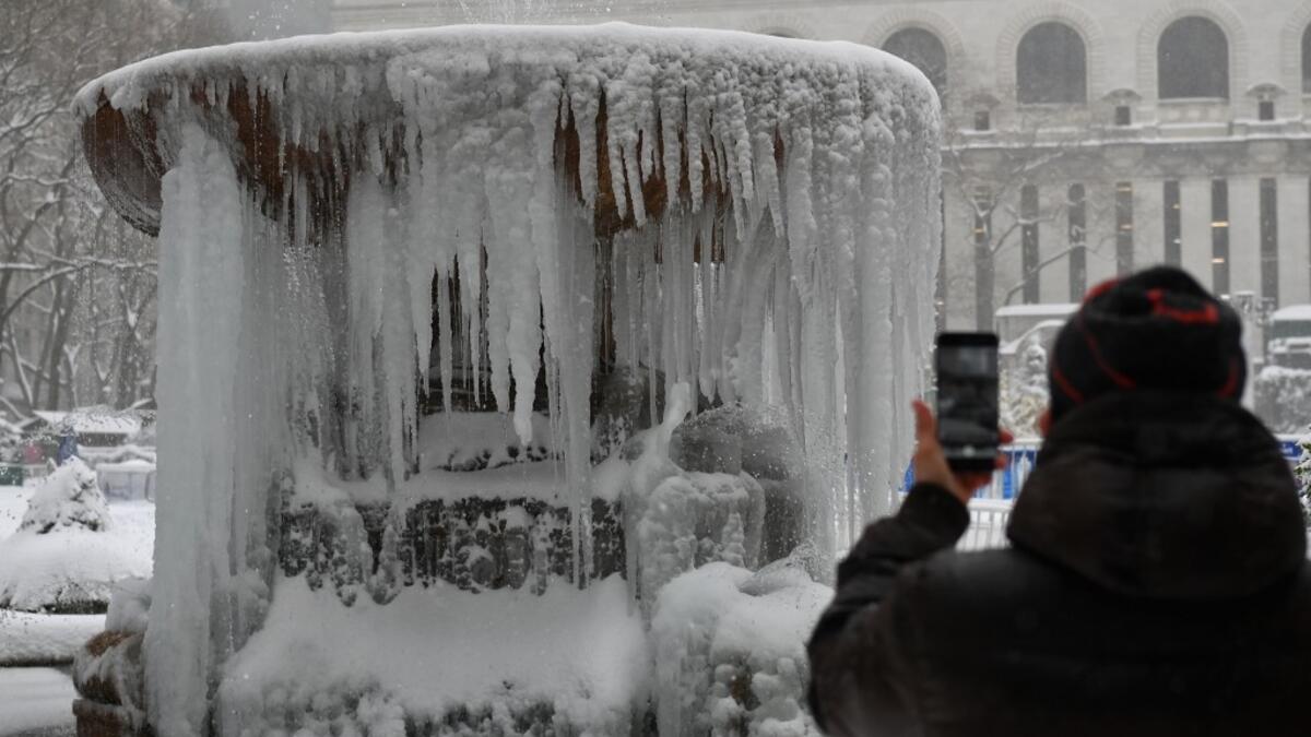A person takes a picture of The Josephine Shaw Lowell Memorial Fountain covered in ice during a winter storm on February 1, 2021 in New York City. A powerful winter storm is set to dump feet of snow along a stretch of the US east coast including New York City on February 1, 2021, after blanketing the nation's capital. Angela Weiss / AFP