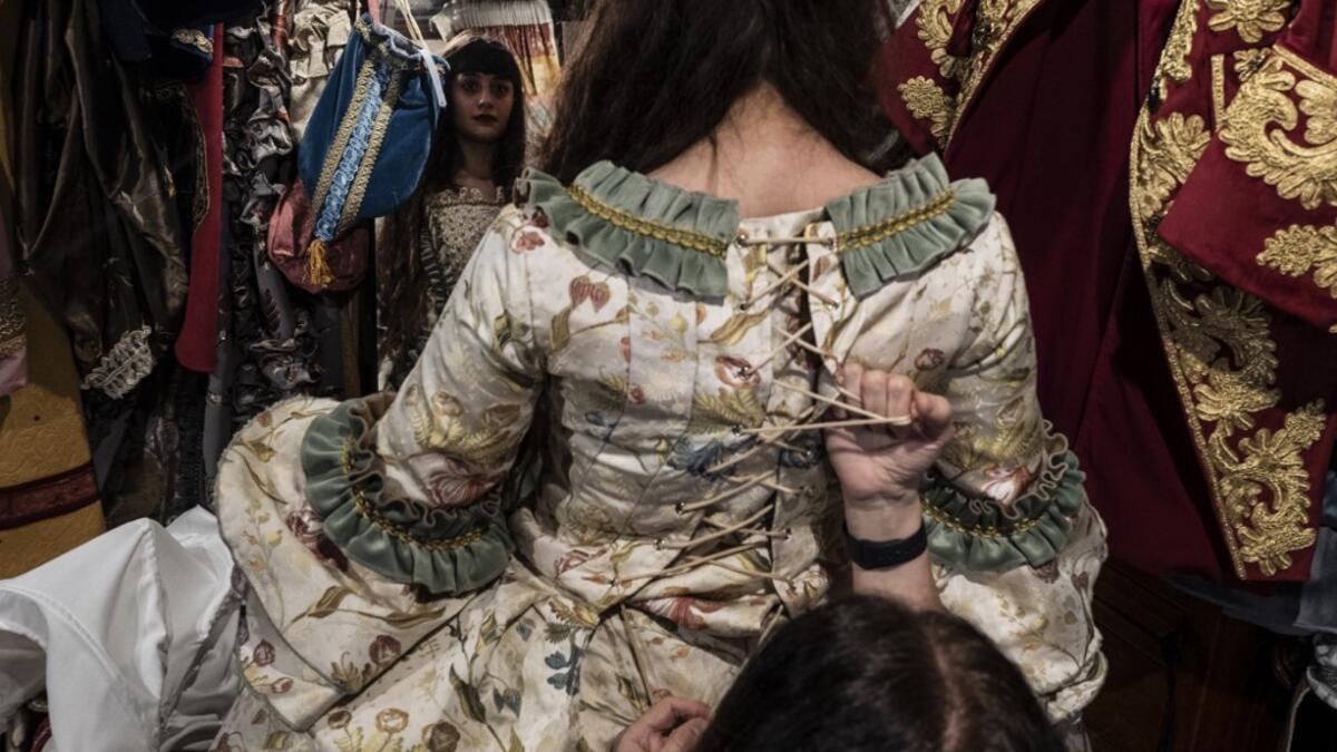 An employee (Front R) helps a reveller put on a traditional carnival costume in 'La Bauta' shop in Venice on February 6, 2021, as the traditional Venice carnival is being cancelled due to the Covid-19 pandemic. Marco Bertorello / AFP