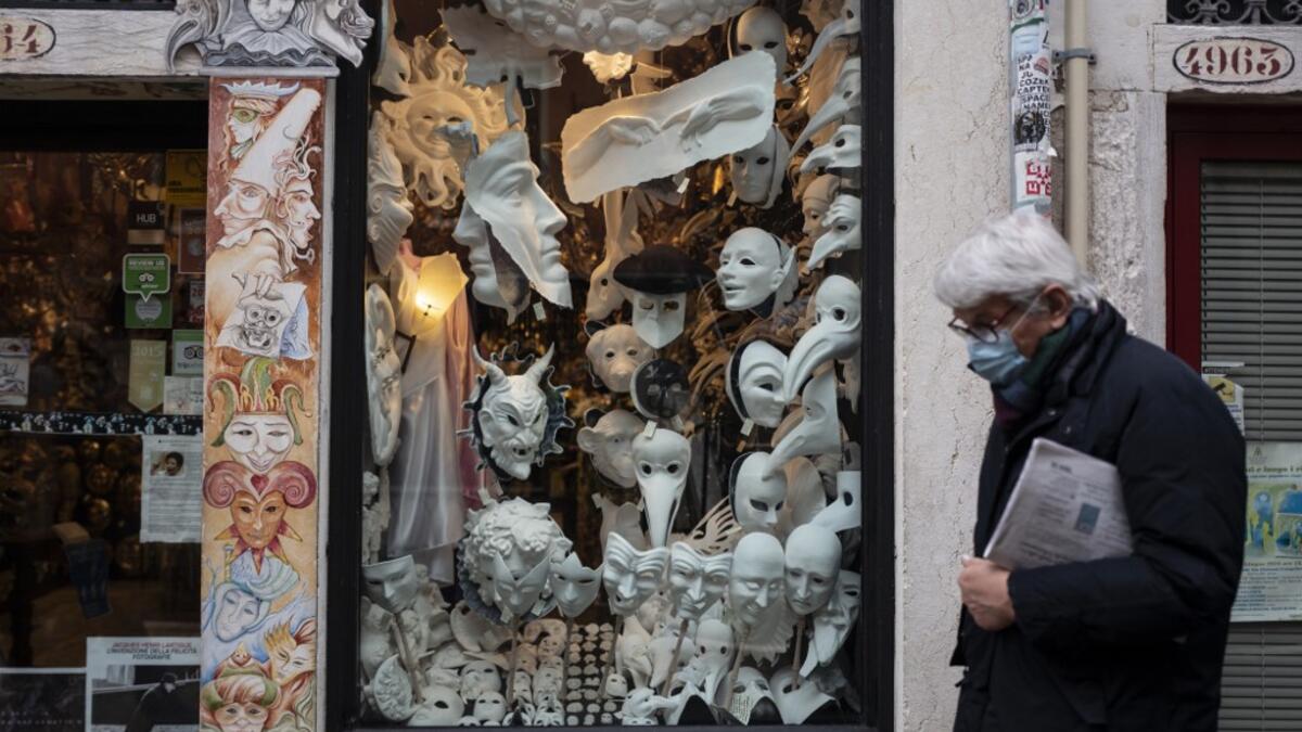 A man wearing a face mask walks past the shop and laboratory 'Ca del Sol' in Venice on February 6, 2021, as the traditional Venice carnival is being cancelled due to the Covid-19 pandemic. Marco Bertorello / AFP