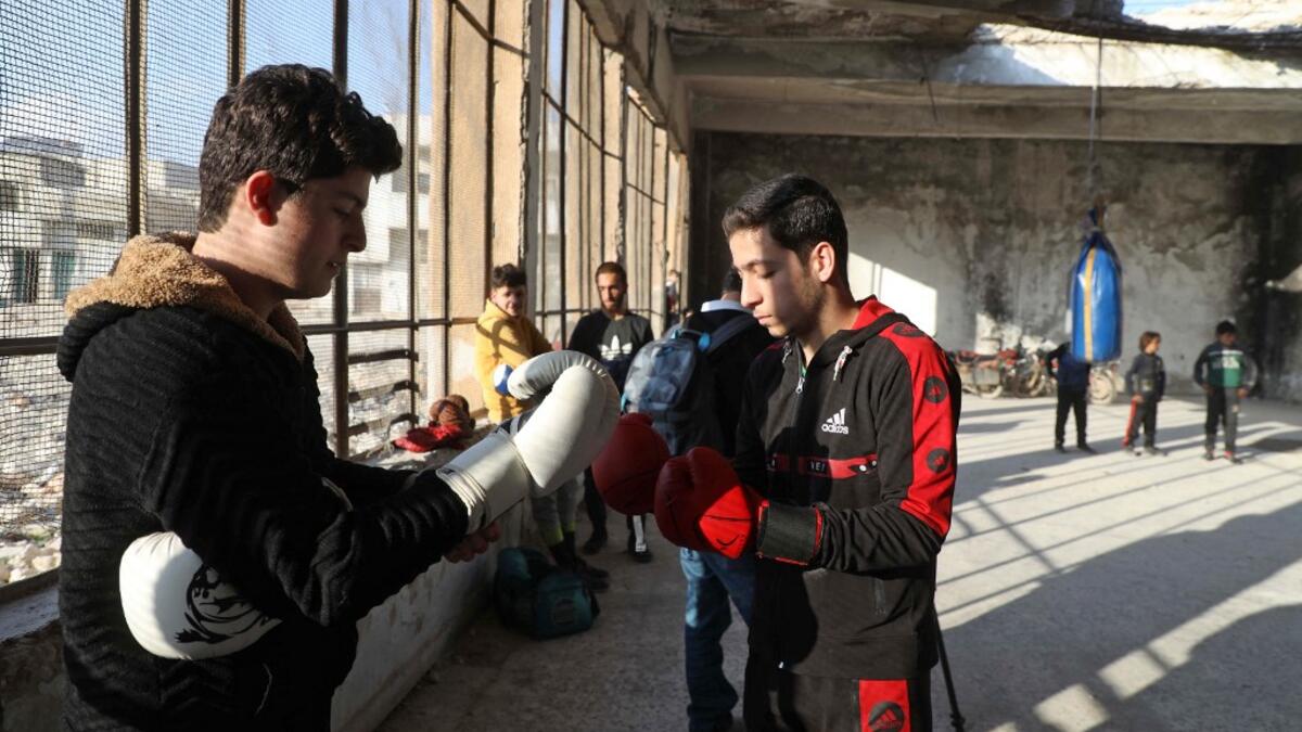 Syrian youths take part in a boxing workout held by local boxer Ahmad Dwara (unseen) inside a damaged building in the town of Atareb in the rebel-held western countryside of Syria's Aleppo province, on February 11, 2021. AAREF WATAD / AFP