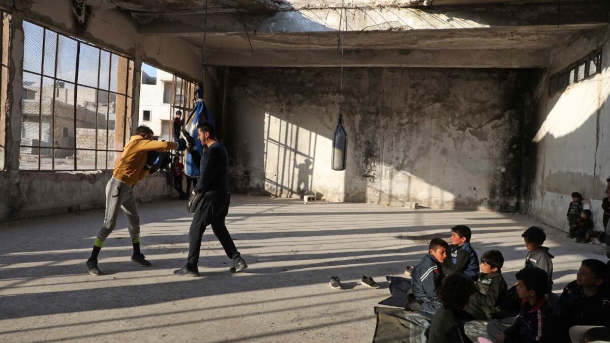 Displaced Syrian boxer Ahmad Dwara trains youth inside a damaged building in the town of Atareb in the rebel-held western countryside of Syria's Aleppo province, on February 11, 2021. AAREF WATAD / AFP