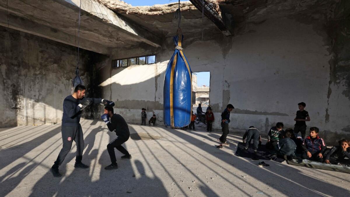 Displaced Syrian boxer Ahmad Dwara trains youth inside a damaged building in the town of Atareb in the rebel-held western countryside of Syria's Aleppo province, on February 11, 2021. AAREF WATAD / AFP
