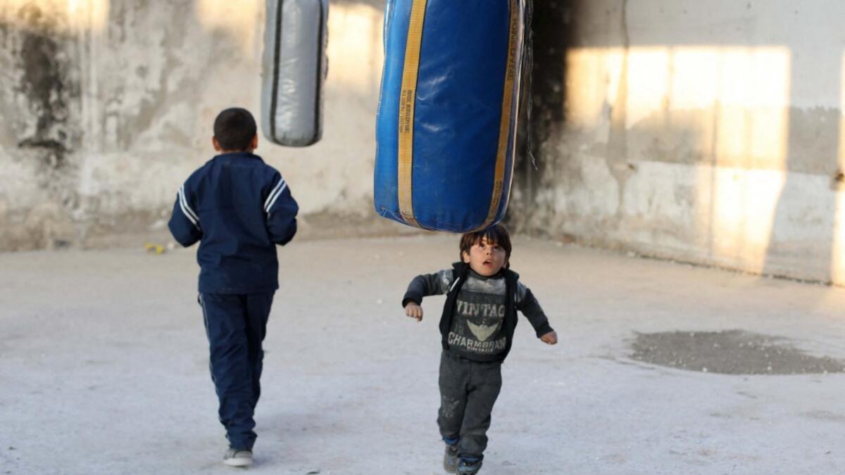 Syrian youths take part in a boxing workout held by local boxer Ahmad Dwara (unseen) inside a damaged building in the town of Atareb in the rebel-held western countryside of Syria's Aleppo province, on February 11, 2021. AAREF WATAD / AFP