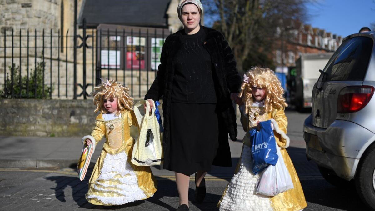 Young children dressed in costume in celebration of the Jewish holiday of Purim, are escorted along a street in the Orthodox Jewish neighborhood of Stamford Hill in north London on February 26, 2021. The carnival-like Purim holiday is celebrated with parades and costume parties to commemorate the deliverance of the Jewish people from a plot to exterminate them in the ancient Persian Empire 2,500 years ago, as recorded in the Biblical Book of Esther. DANIEL LEAL-OLIVAS / AFP