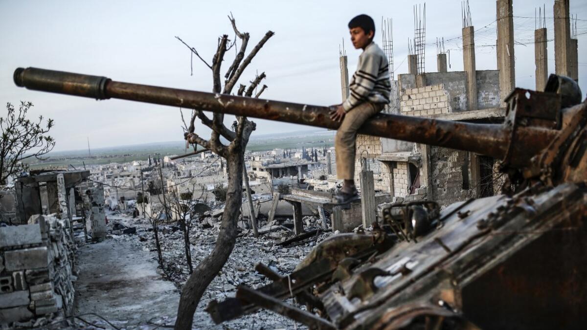 Syrian Kurdish boy sits on a destroyed tank in the Syrian town of Kobane