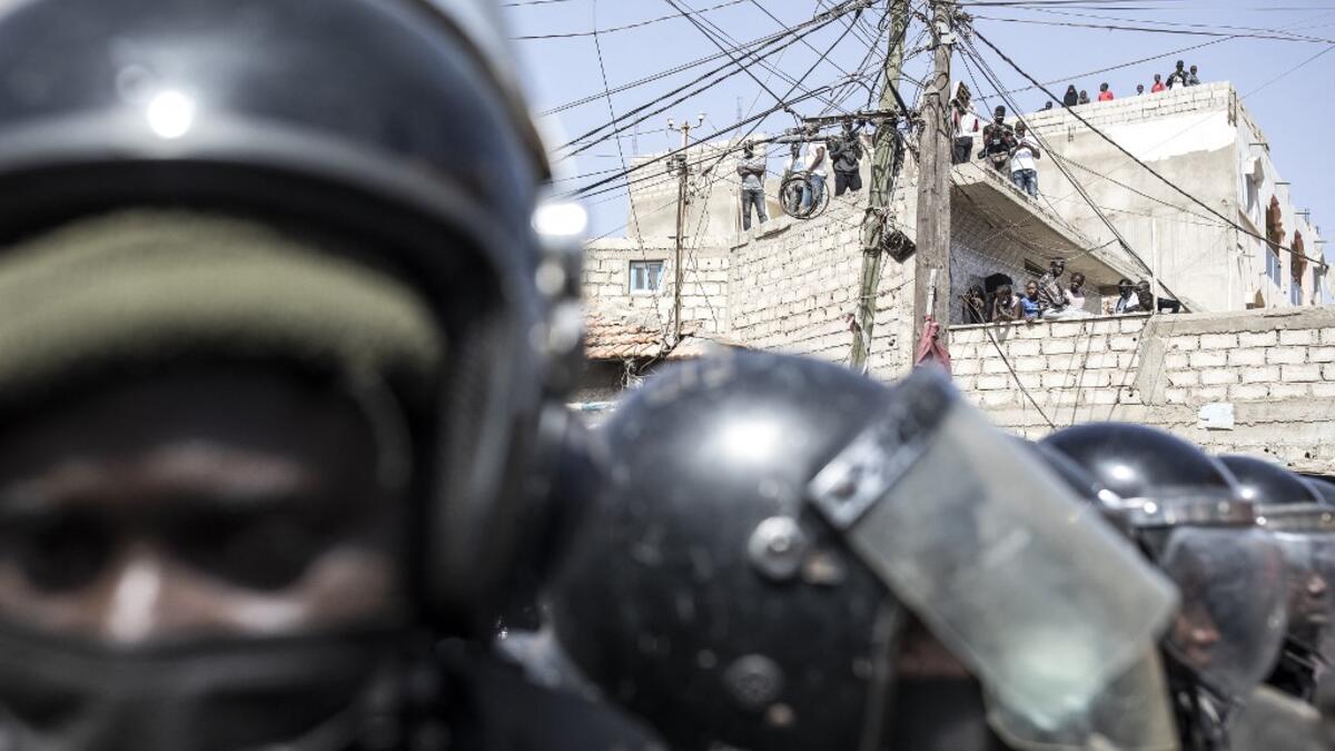 People gather on roofs to watch as police block supporters of main opposition candidate, Ousmane Sonko, outside the Justice Palace in Dakar on March 8, 2021. Protests have been ongoing after opposition leader Ousmane Sonko was arrested following rape charges. JOHN WESSELS / AFP