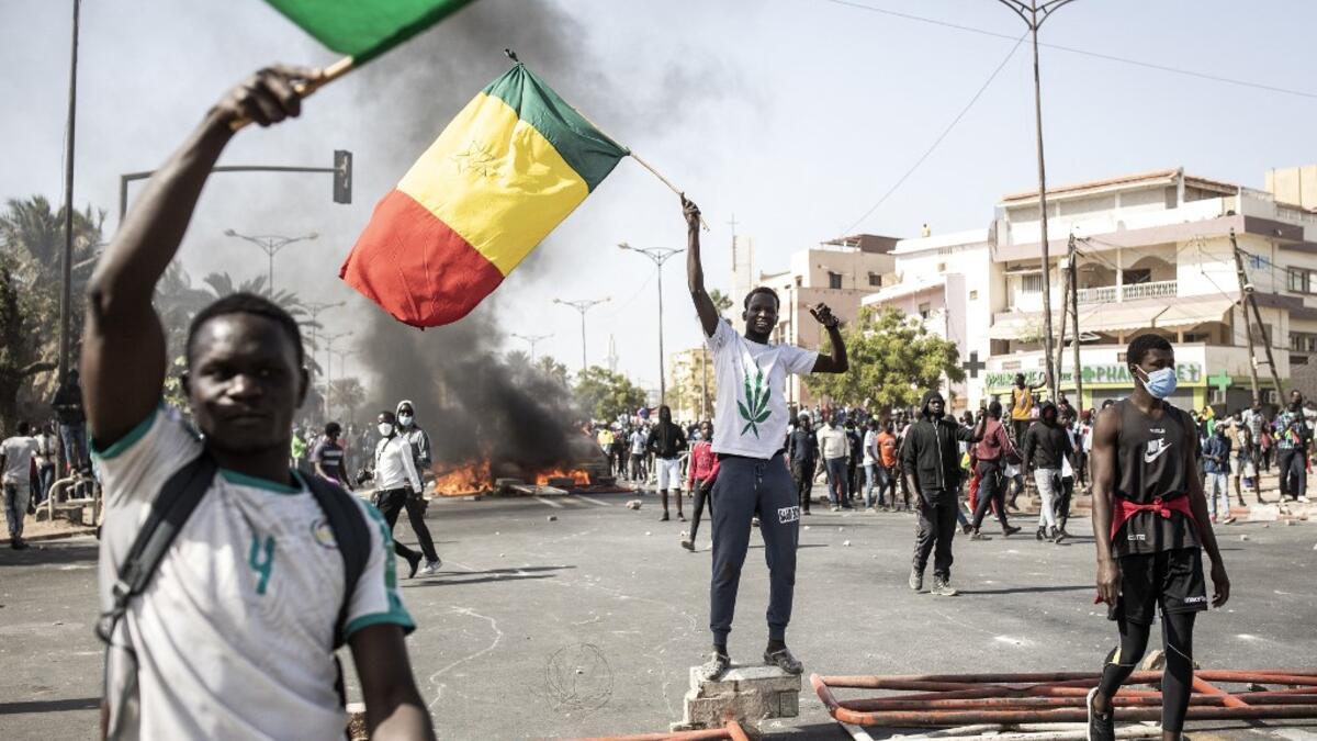 Protesters wave the Senegalese national flag during a protest in Dakar on March 8, 2021, after the country's opposition leader Ousmane Sonko was charged with rape. Usually considered a beacon of stability in a volatile region, deadly clashes between opposition supporters and security forces have rocked the West African state. JOHN WESSELS / AFP