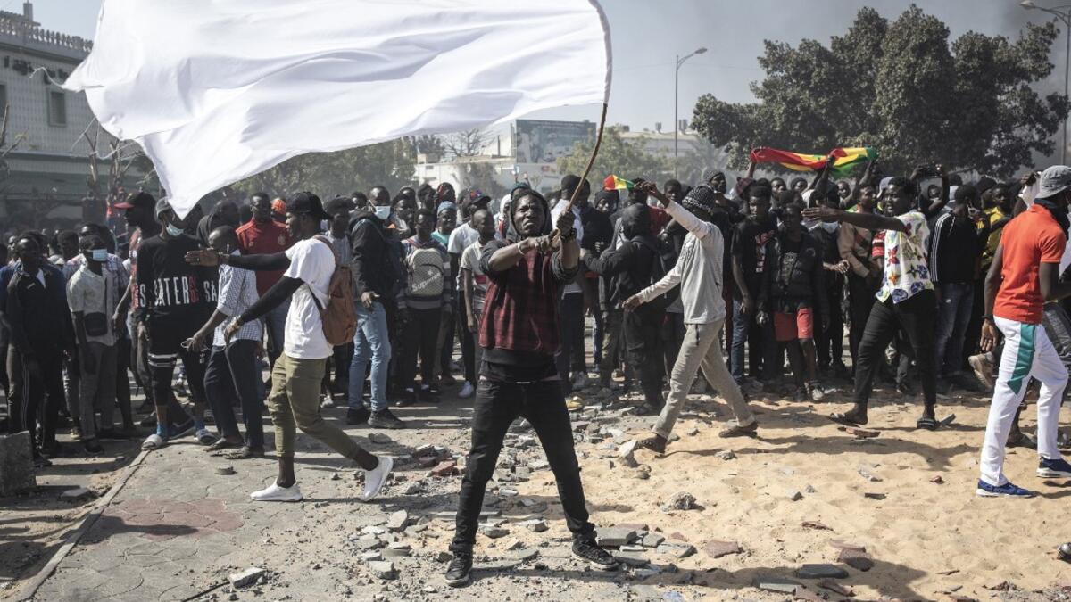 A protester waves a white flag during a protest in Dakar on March 8, 2021, after the country's opposition leader Ousmane Sonko was charged with rape. Usually considered a beacon of stability in a volatile region, deadly clashes between opposition supporters and security forces have rocked the West African state. JOHN WESSELS / AFP