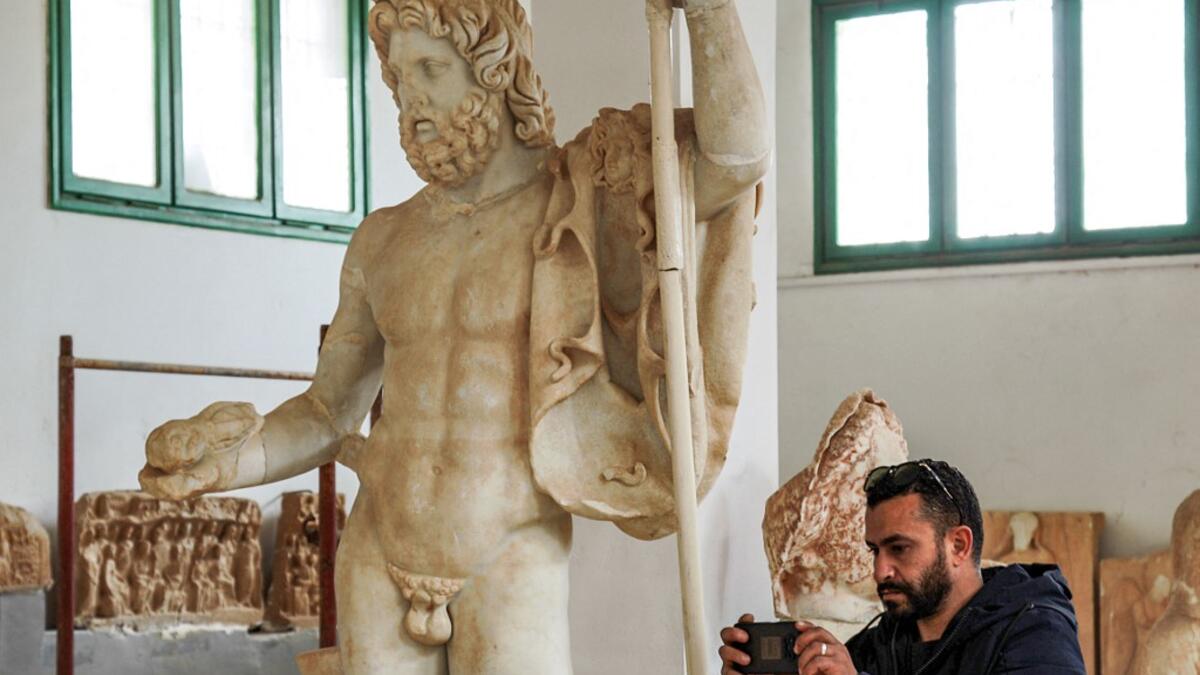 A man uses a phone to take a picture of a Roman statue of Jupiter