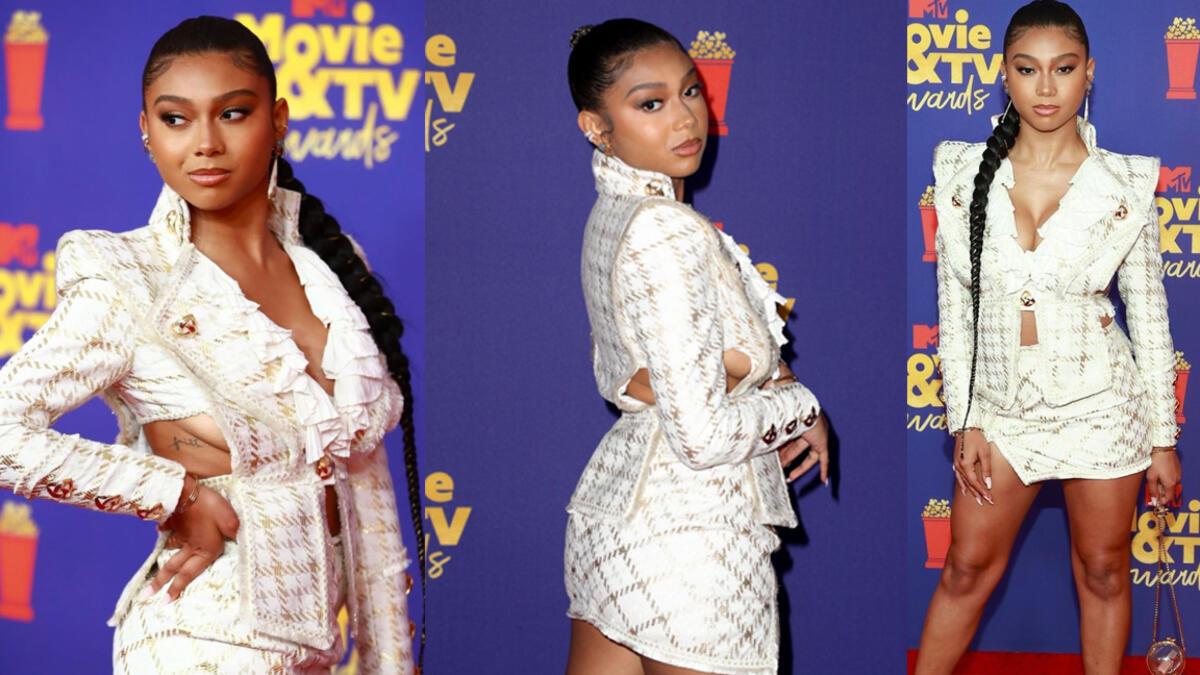 Sierra Capri In a Haleia white and gold blazer skirt set, which she paired with lucite heels, lucite handbag and pendant earrings.