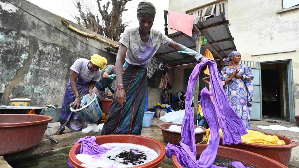 Dyers dye cotton fabric at Pathe'O house in the popular district of Treichville in Abidjan on March 31, 2021. A small self-taught tailor in his early years, the Ivorian-Burkinabe Pathe'O became the designer of African heads of state and celebrates the fiftieth anniversary of his brand, leading the "fight" for the recognition of fashion on the continent.