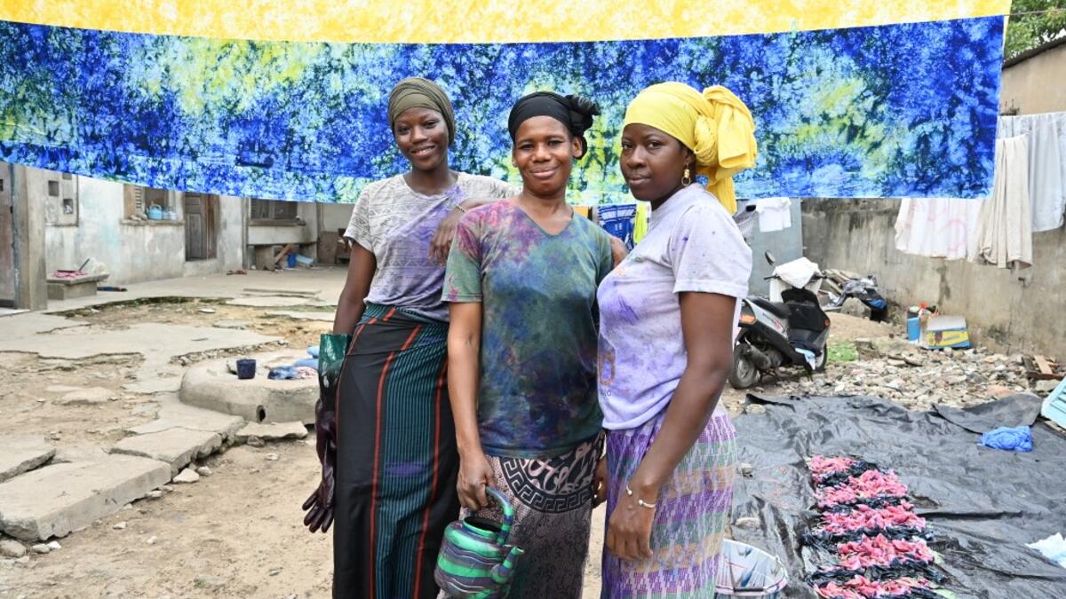 Dyers pose for a photograph at Pathe'O house in the popular district of Treichville in Abidjan on March 31, 2021. A small self-taught tailor in his early years, the Ivorian-Burkinabe Pathe'O became the designer of African heads of state and celebrates the fiftieth anniversary of his brand, leading the "fight" for the recognition of fashion on the continent