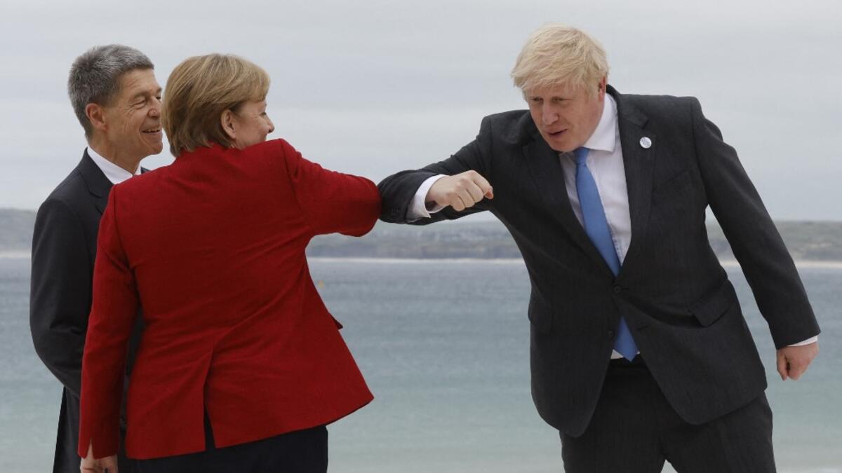Britain's Prime Minister Boris Johnson (R) elbow-bumps Germany's Chancellor Angela Merkel as he greets her and her husband Joachim Sauer at the G7 summit in Carbis Bay, Cornwall on June 11, 2021. G7 leaders from Canada, France, Germany, Italy, Japan, the UK and the United States meet this weekend for the first time in nearly two years, for three-day talks in Carbis Bay, Cornwall