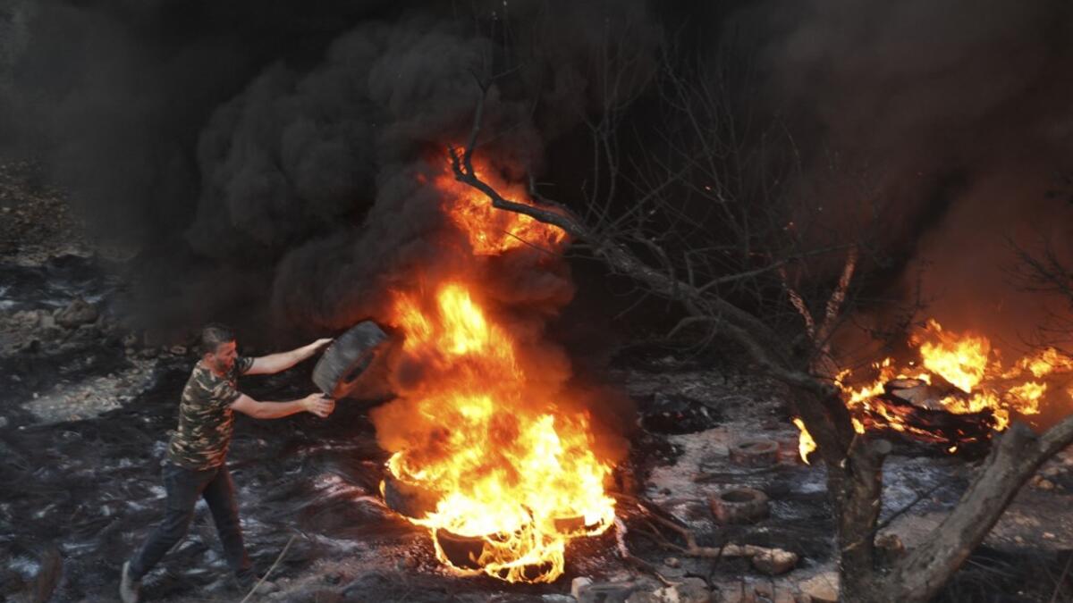 A Palestinian man sets a tire on fire in the village of Beita, south of Nablus, in the occupied West Bank, across the valley from the newly built Israeli settlers' outpost of Eviatar, on June 13, 2021. With flashing lasers, honking horns and choking smoke from burning tires, the latest tactics used by Palestinian protesters are dusk till dawn rallies to make life unbearable for Israeli settlers