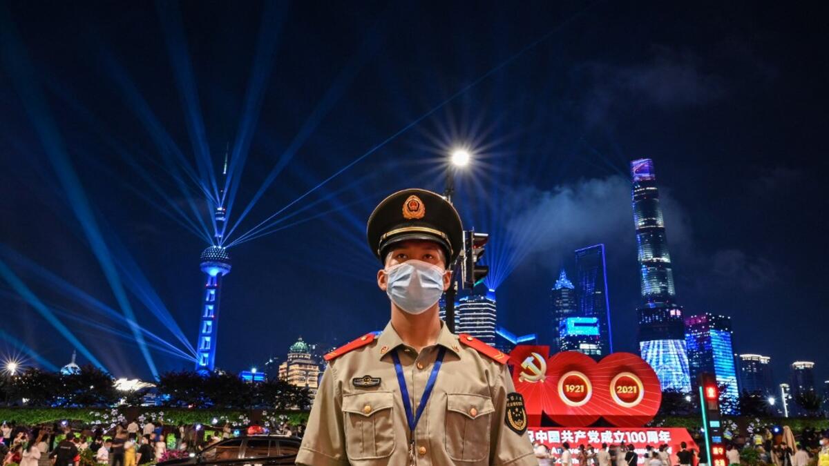 A Chinese paramilitary police stands guard while a light show is seen from the Bund in Shanghai on June 30, 2021, on the eve of the 100th anniversary of the Chinese Communist Party.