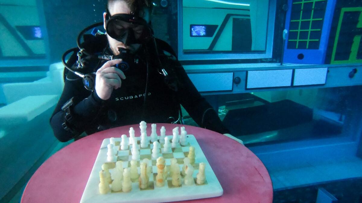 A diver plays mock chess as he experiences Deep Dive Dubai, the deepest swimming pool in the world reaching 60m, in the United Arab Emirates, on July 10, 2021. The city of superlatives, with the world's tallest tower among its many records, Dubai now has the deepest swimming pool on the planet complete with a "sunken city" for divers to explore. GIUSEPPE CACACE / AFP