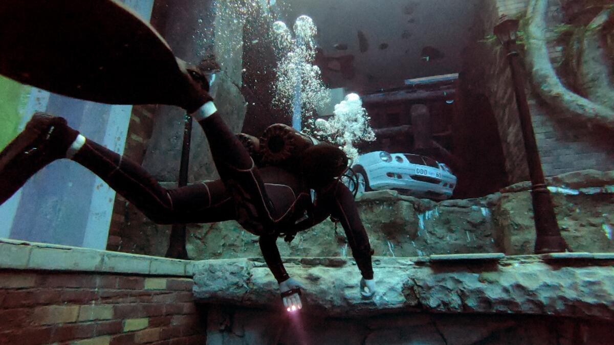 A diver explores a mock sunken city as he experiences Deep Dive Dubai, the deepest swimming pool in the world reaching 60m, in the United Arab Emirates, on July 10, 2021. The city of superlatives, with the world's tallest tower among its many records, Dubai now has the deepest swimming pool on the planet complete with a "sunken city" for divers to explore. GIUSEPPE CACACE / AFP