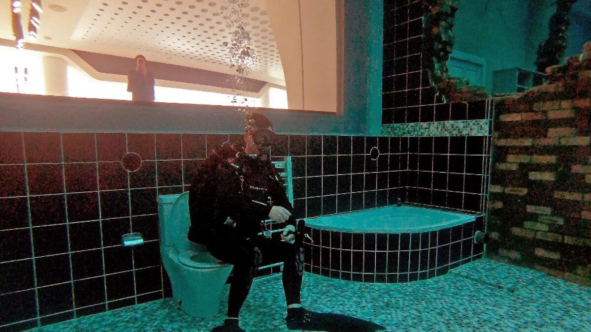 A diver explores a mock sunken city as he experiences Deep Dive Dubai, the deepest swimming pool in the world reaching 60m, in the United Arab Emirates, on July 10, 2021. The city of superlatives, with the world's tallest tower among its many records, Dubai now has the deepest swimming pool on the planet complete with a "sunken city" for divers to explore. GIUSEPPE CACACE / AFP
