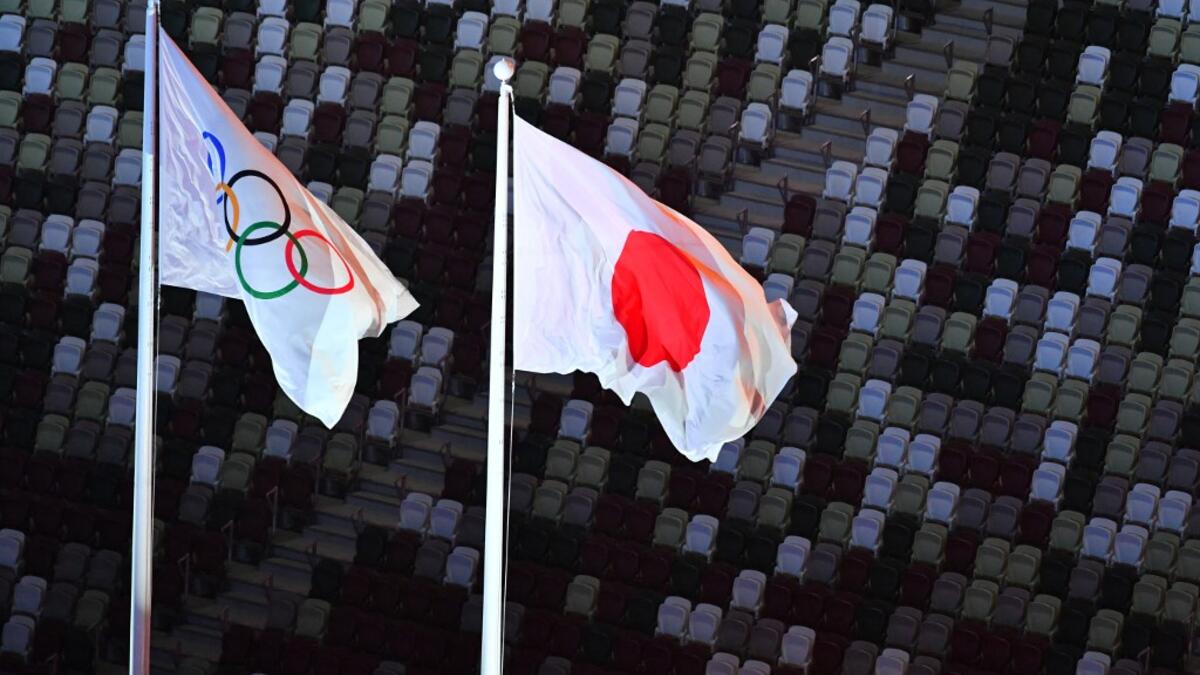 An overview shows the Olympic (L) and Japan's national flag fluttering with empty stands seen in the background during the opening ceremony of the Tokyo 2020 Olympic Games, at the Olympic Stadium, in Tokyo