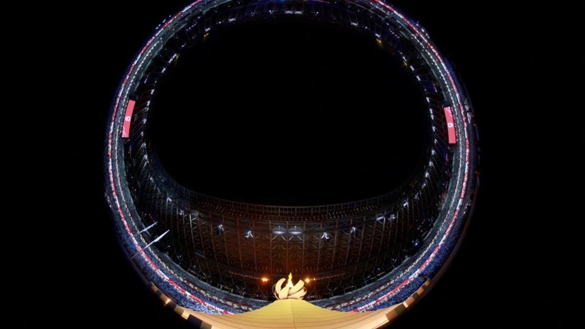 This picture taken with a fish-eye lens shows the Olympic cauldron and flame during the opening ceremony of the Tokyo 2020 Olympic Games, at the Olympic Stadium, in Tokyo