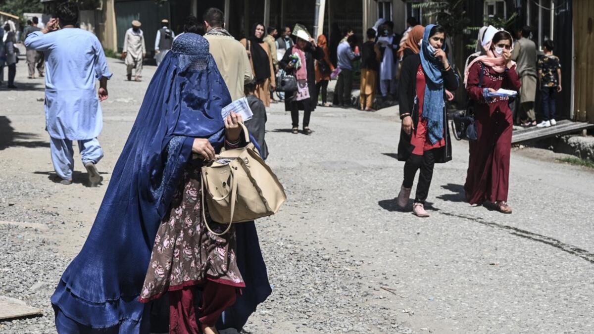 A woman wearing a burqa arrives to submit a passport application at an office in Kabul on July 25, 2021. Dozens begin lining up at the passport office in Kabul before dawn most days, and by eight in the morning the queue already stretches for a good hundred metres.