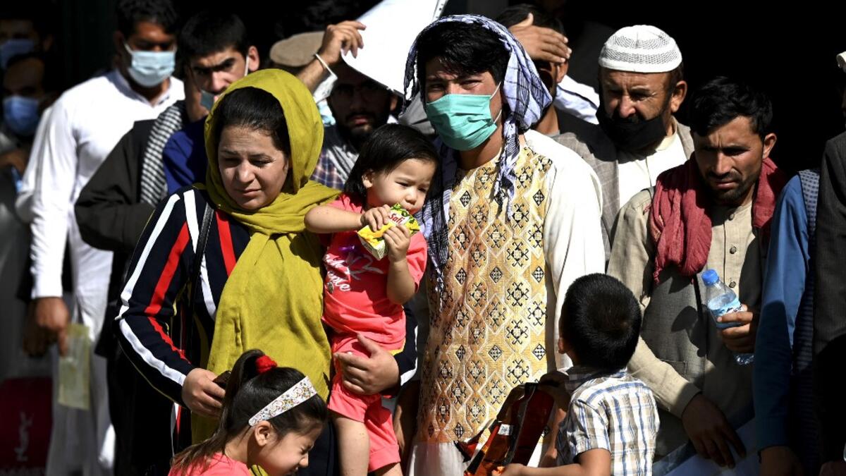 A family stand in a queue to submit their passport applications at an office in Kabul on July 25, 2021. Dozens begin lining up at the passport office in Kabul before dawn most days, and by eight in the morning the queue already stretches for a good hundred metres.