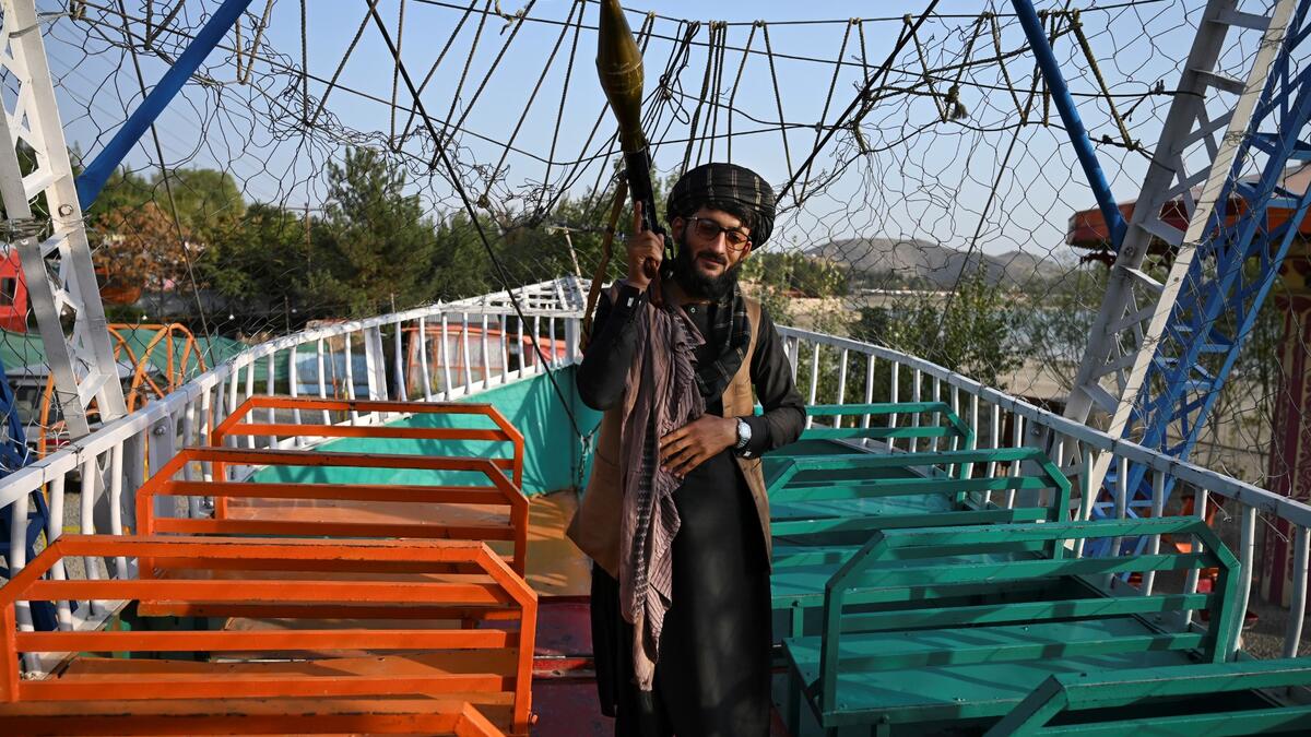 Taliban fighter carrying a rocket propelled grenade (RPG) launcher stands on pirate ship ride in a fairground at Qargha Lake on the outskirts of Kabul. "This is Afghanistan!" a Taliban fighter shouts on the pirate ship ride at a fairground in western Kabul, as his armed comrades cackle and whoop on board the rickety attraction. (Photo by WAKIL KOHSAR / AFP) / TO GO WITH: AFGHANISTAN-CONFLICT-FAIRGROUND, SCENE BY JAMES EDGAR - TO GO WITH: Afghanistan-conflict-fairground, SCENE by James EDGAR