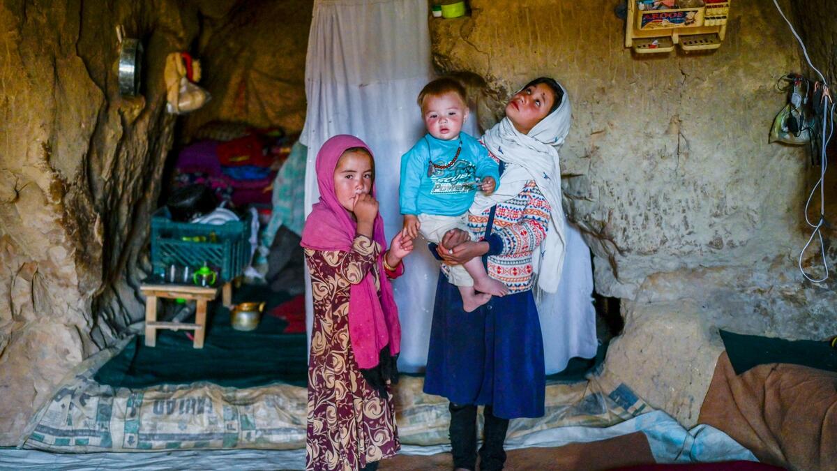 In this picture taken on October 3, 2021, Hazara ethnic children stand in their cave on a cliff pockmarked by caves where people still live as they did centuries ago in Bamiyan.