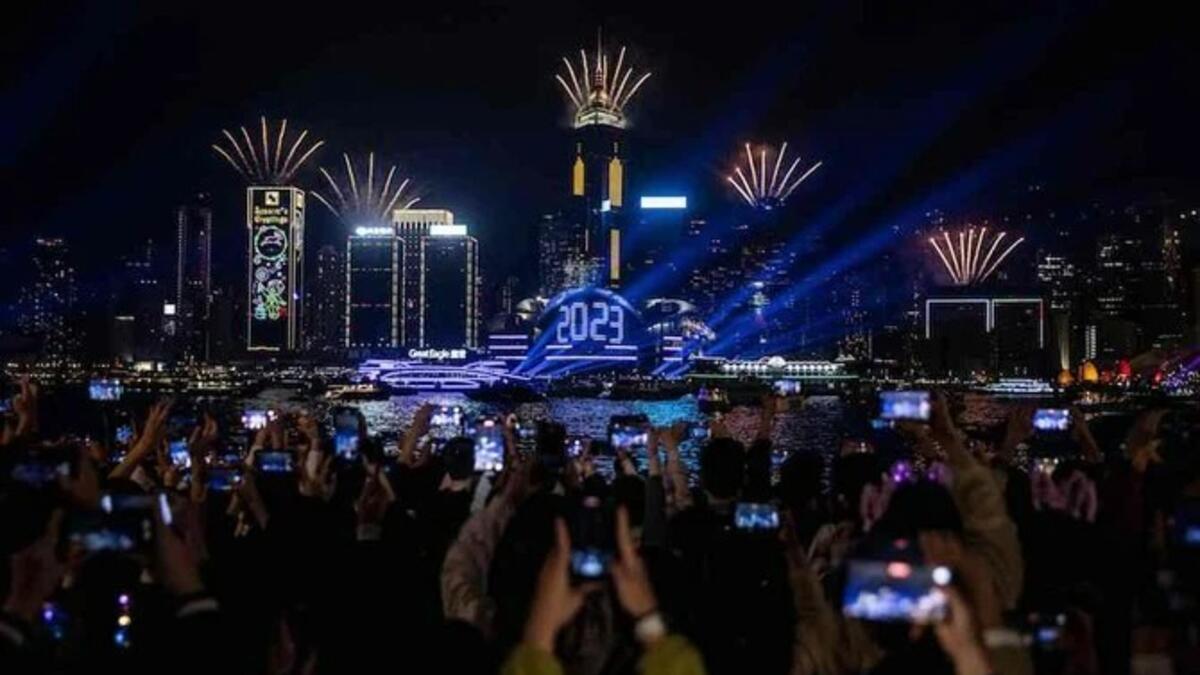 المحتفلون يشاهدون الألعاب النارية وعرض الليزر أثناء احتفالهم بالعام الجديد بجوار ميناء فيكتوريا في هونغ كونغ في 1 يناير 2023. (AFPP)