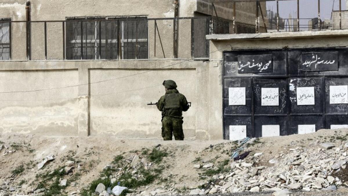 A member of the Russian military police stands guard at the Wafideen checkpoint on the outskirts of the Syrian capital Damascus neighboring the rebel-held Eastern Ghouta enclave on Mar. 13, 2018, awaiting any civilians evacuating from the area.  (Louai Beshara / AFP)