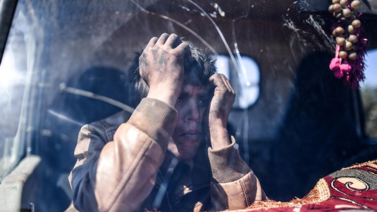 A young boy waits at a check point in the village of Anab ahead of crossing to the Turkish-backed Syrian rebels side on Mar. 17, 2018, as civilians flee the city of Afrin in northern Syria. (BULENT KILIC / AFP)