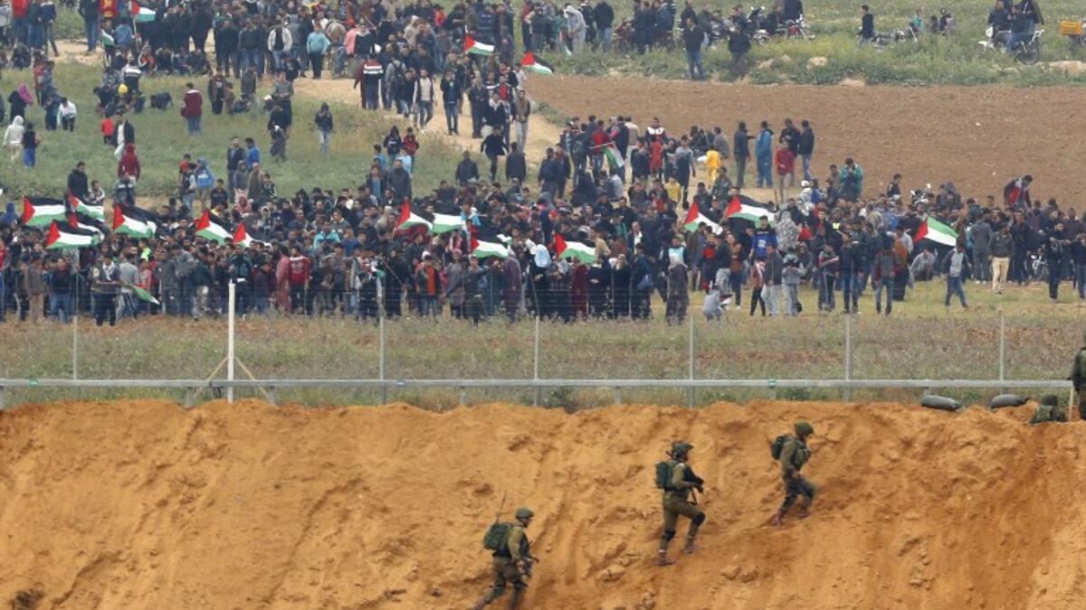 A picture taken on March 30, 2018 from the southern Israeli kibbutz of Nahal Oz across the border from the Gaza strip shows Palestinians participating in a tent city protest commemorating Land Day, with Israeli soldiers seen below in the foreground. 
(Jack GUEZ / AFP)