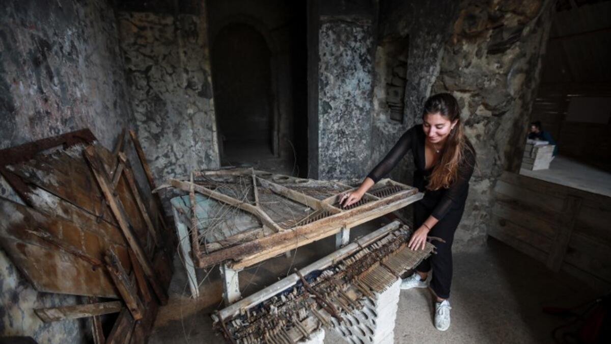 Woman touching the remains of a destroyed piano in a room at the Sofar Grand Hotel in the Lebanese village of Sofar, some 30 kilometres (20 miles) east of Beirut (AFP)
