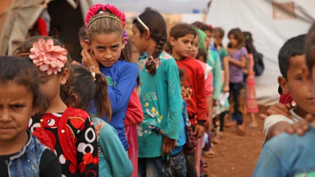 Syrian children who fled with their families from the northern countryside of Hama, line up in the yard of the makeshift school of "Zuhur al-Mustaqbal" (in Arabic "Flowers of the Future") in al-Jeneinah camp for displaced people in the village of Atme, in Syria's mostly rebel-held northern Idlib province, on October 1, 2018. Aaref WATAD / AFP