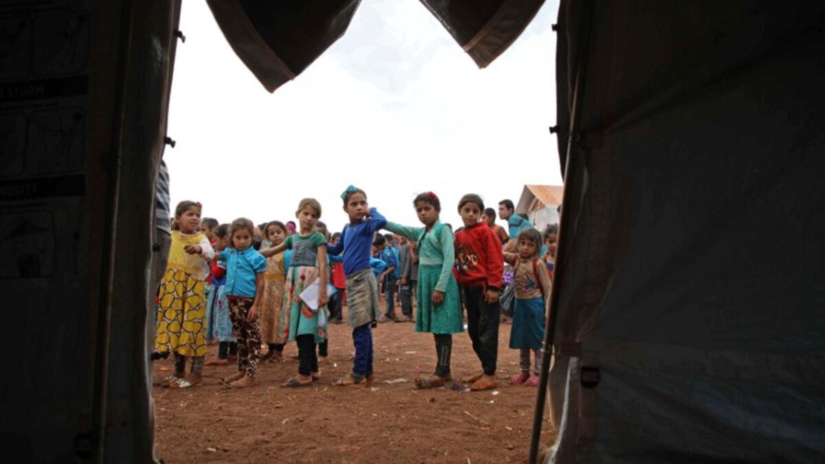 Syrian children who fled with their families from the northern countryside of Hama, line up in the yard of the makeshift school of "Zuhur al-Mustaqbal" (in Arabic "Flowers of the Future") in al-Jeneinah camp for displaced people in the village of Atme, in Syria's mostly rebel-held northern Idlib province, on October 1, 2018. Aaref WATAD / AFP