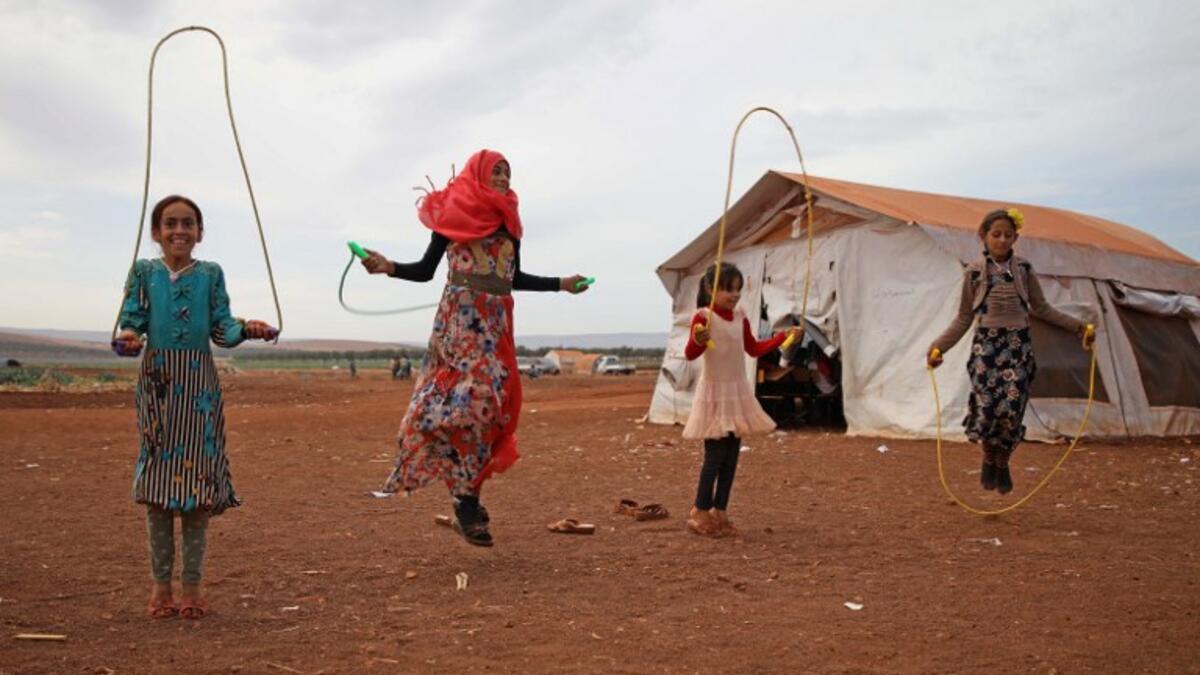 Syrian children who fled with their families from the northern countryside of Hama, jump rope in the yard of the makeshift school of "Zuhur al-Mustaqbal" (in Arabic "Flowers of the Future") in al-Jeneinah camp for displaced people in the village of Atme, in Syria's mostly rebel-held northern Idlib province, on October 1, 2018. Aaref WATAD / AFP