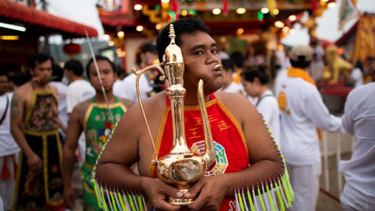 A devotee of the Loem Hu Thai Su shrine has a metal jug pierced through his cheek during the annual Vegetarian Festival in Phuket on October 12, 2018. Jewel SAMAD/AFP