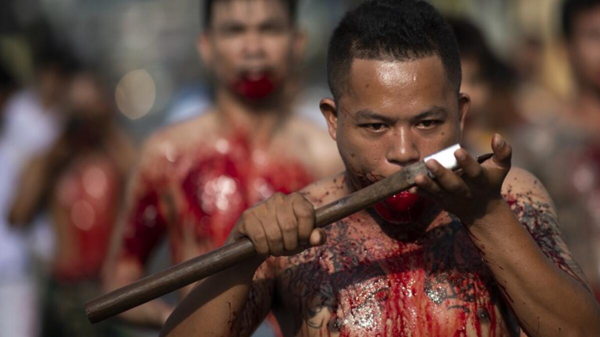 A devotee of the Loem Hu Thai Su shrine cuts his tongue on an axe as he parades during the annual Vegetarian Festival in Phuket on October 12, 2018. Jewel SAMAD/AFP