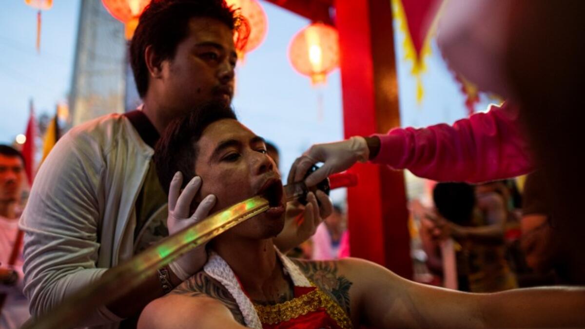 A devotee of the Loem Hu Thai Su shrine has a sword pierced through his cheek during the annual Vegetarian Festival in Phuket on October 12, 2018. Jewel SAMAD/AFP
