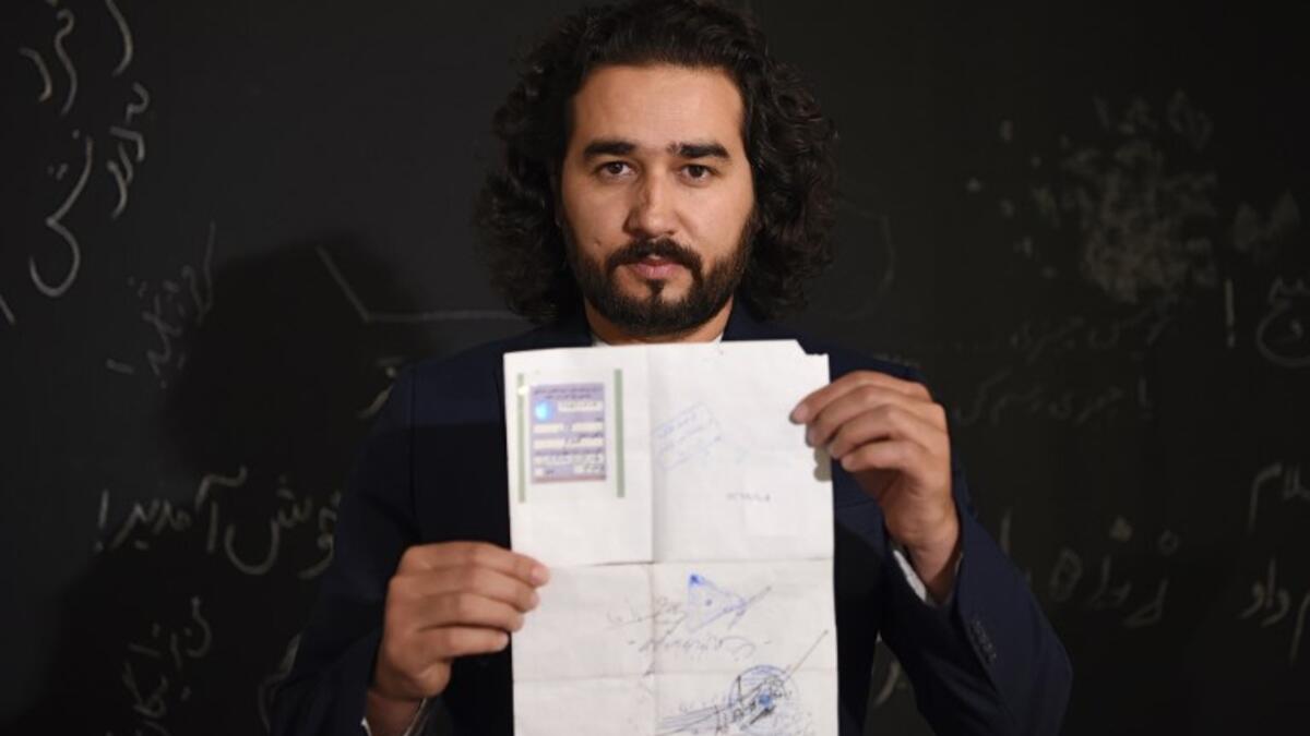 In this photo taken on October 8, 2018, Afghan co-founder and president of ArtLords Omaid Sharifi, 32, poses for a picture as he holds his id card or Tazkira registered to vote in the upcoming parliamentary election, in Kabul. 
WAKIL KOHSAR / AFP
