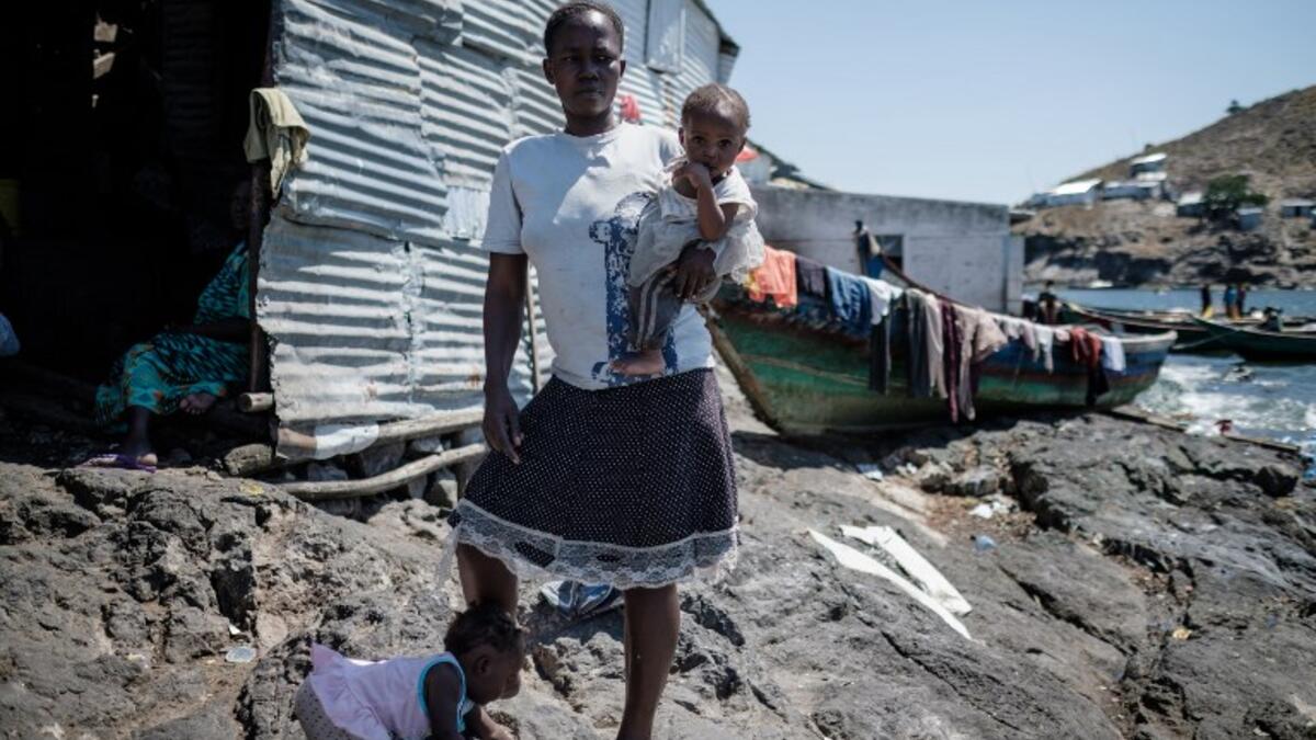 A woman holds her baby on Migingo island on October 5, 2018 which is densely populated by residents fishing mainly for Nile perch in Lake Victoria on the border of Uganda and Kenya. 
Yasuyoshi CHIBA / AFP