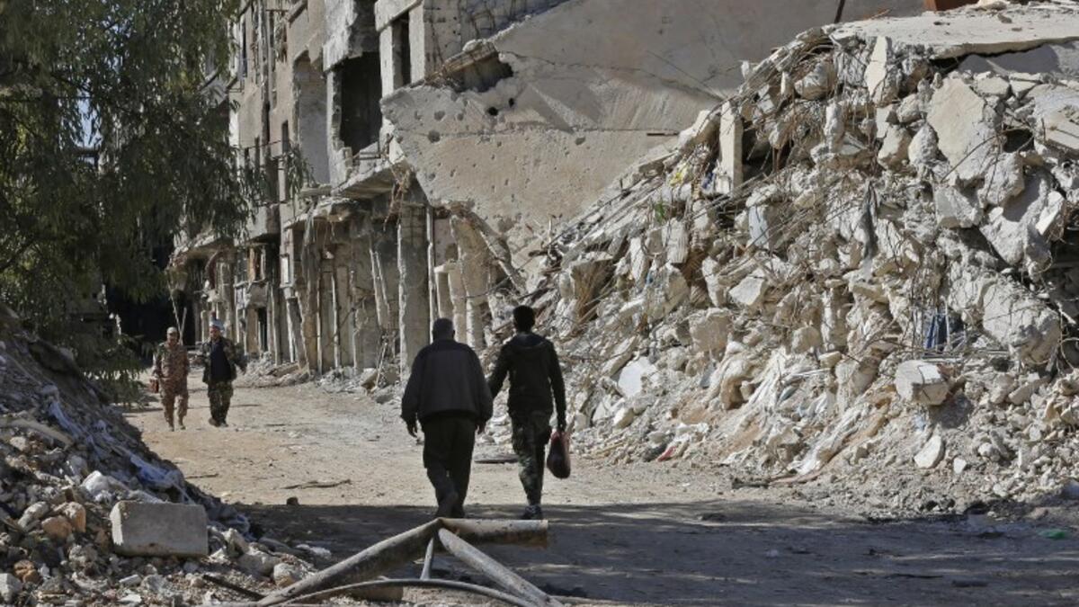 People walk past destroyed buildings in the Palestinian camp of Yarmuk southern Damascus on November 1, 2018. 
LOUAI BESHARA / AFP