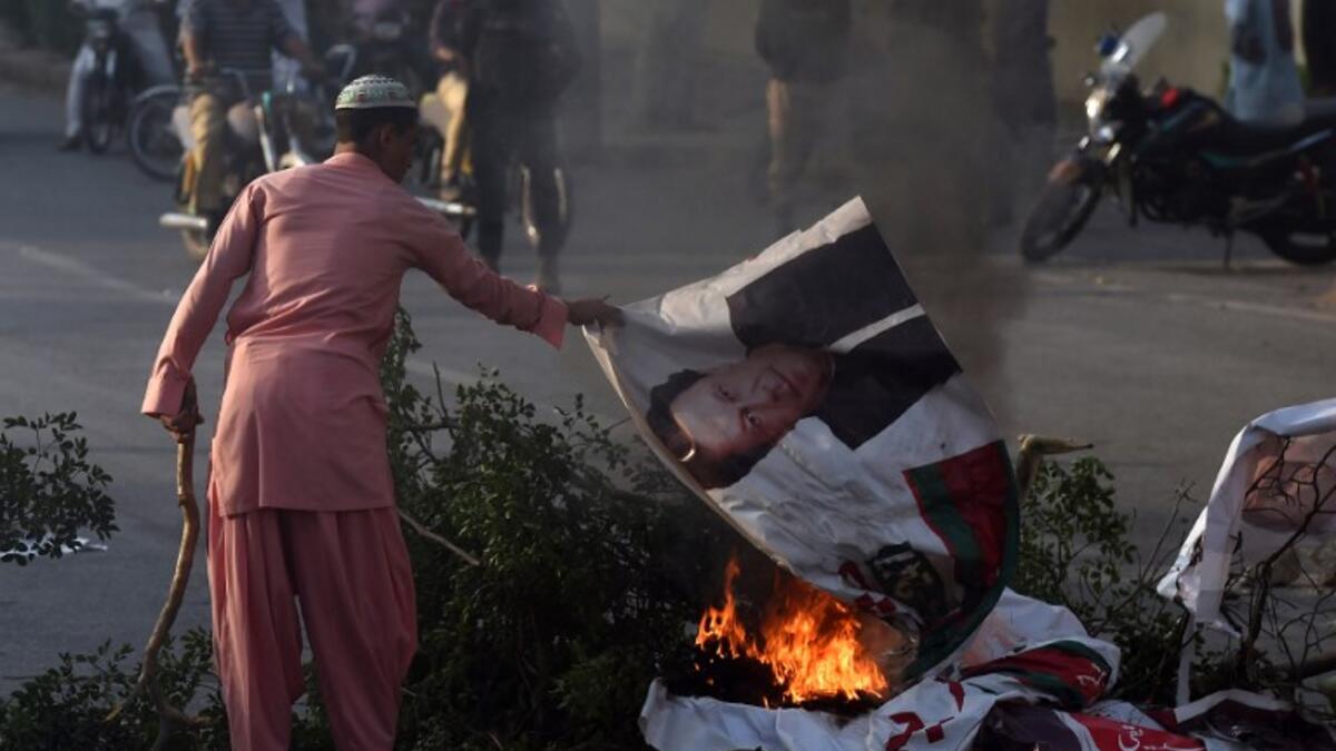 A supporter of Pakistan's religious hardline party Jamiat Ulema Islam (JUI) burns a poster of Pakistan's Prime Minister Imran Khan on a block street during a protest following the Supreme Court's decision to acquit Pakistani Christian woman Asia Bibi. (ASIF HASSAN / AFP)