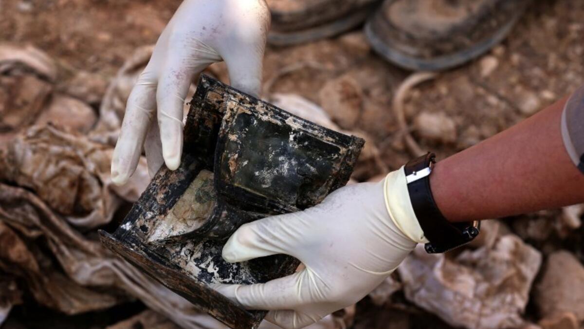 a member of the Yazidi minority searches in a wallet for clues, that might lead him to missing relatives in the remains of people killed by the Islamic State. (Safin HAMED / AFP)