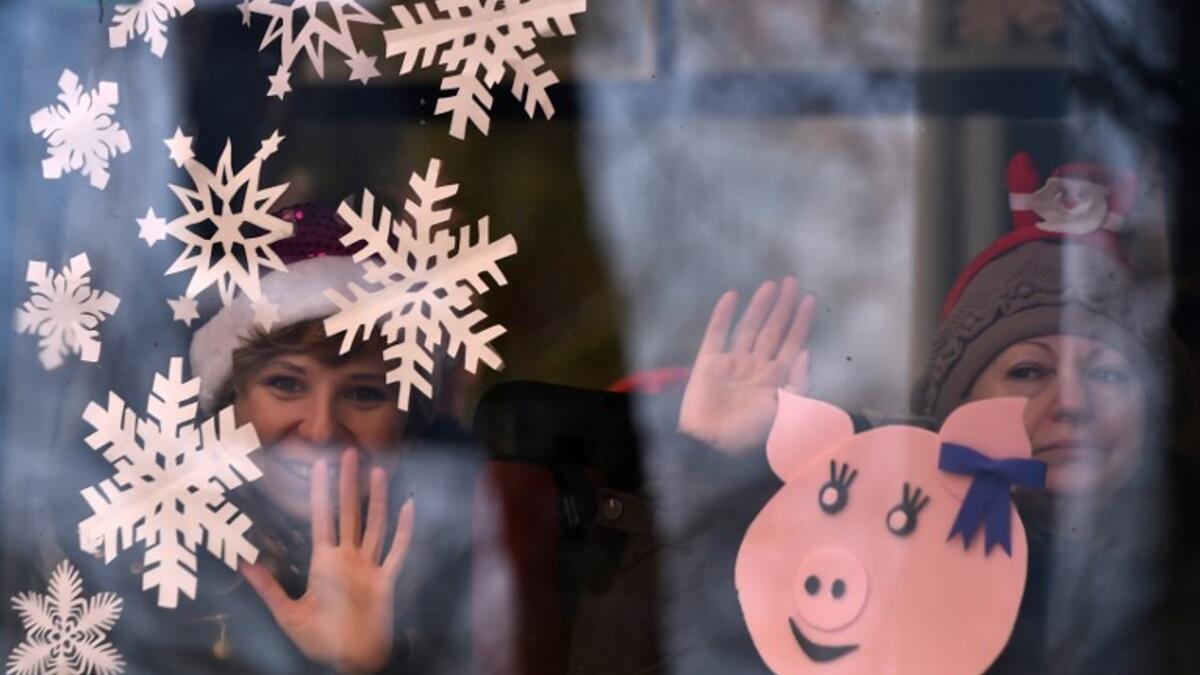 Women wave from a bus window during the New Year's car parade in the town of Vileyka about 100 km northwest from Russia's Minsk on December 29, 2018. 
Sergei GAPON / AFP