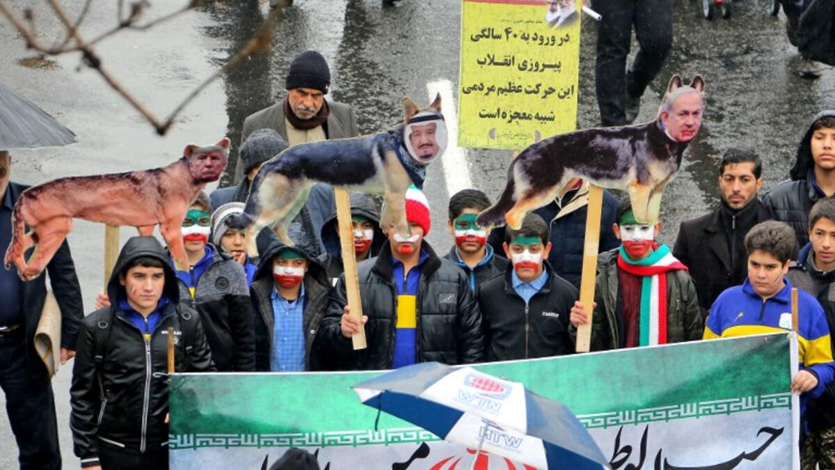 Iranian children, some with face paint in the national flag's colours, pose behind a banner depicting the national flag and with signs depicting dogs with the faces of (L to R) US President Donald Trump, Saudi King Salman bin Abdulaziz, and Israeli Prime Minister Benjamin Netanyahu.
ATTA KENARE / AFP