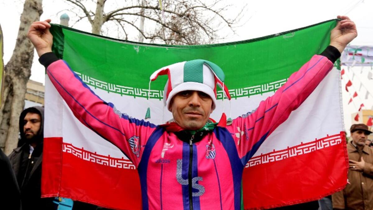 An Iranian man wearing a jester's hat coloured with the national flag's colours poses with a national flag during commemorations of the 40th anniversary of Islamic Revolution in the capital Tehran on February 11, 2019. 
ATTA KENARE / AFP