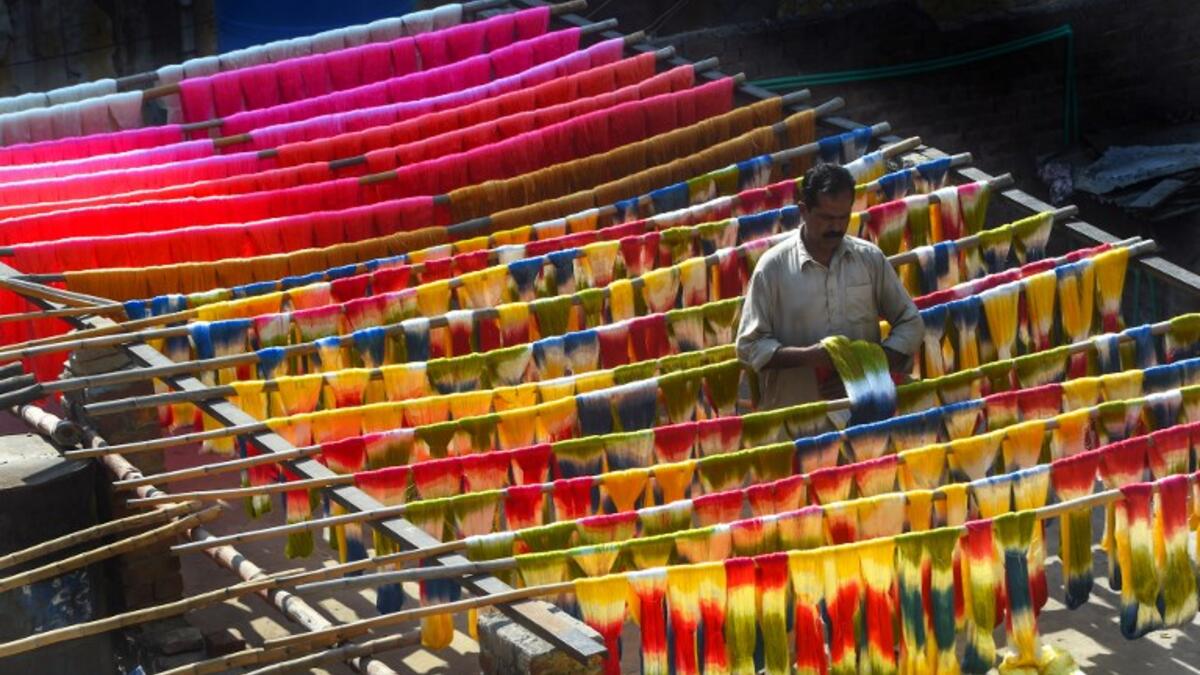 A Pakistani worker dries fabric threads after dyeing them at a factory in Lahore 
ARIF ALI / AFP