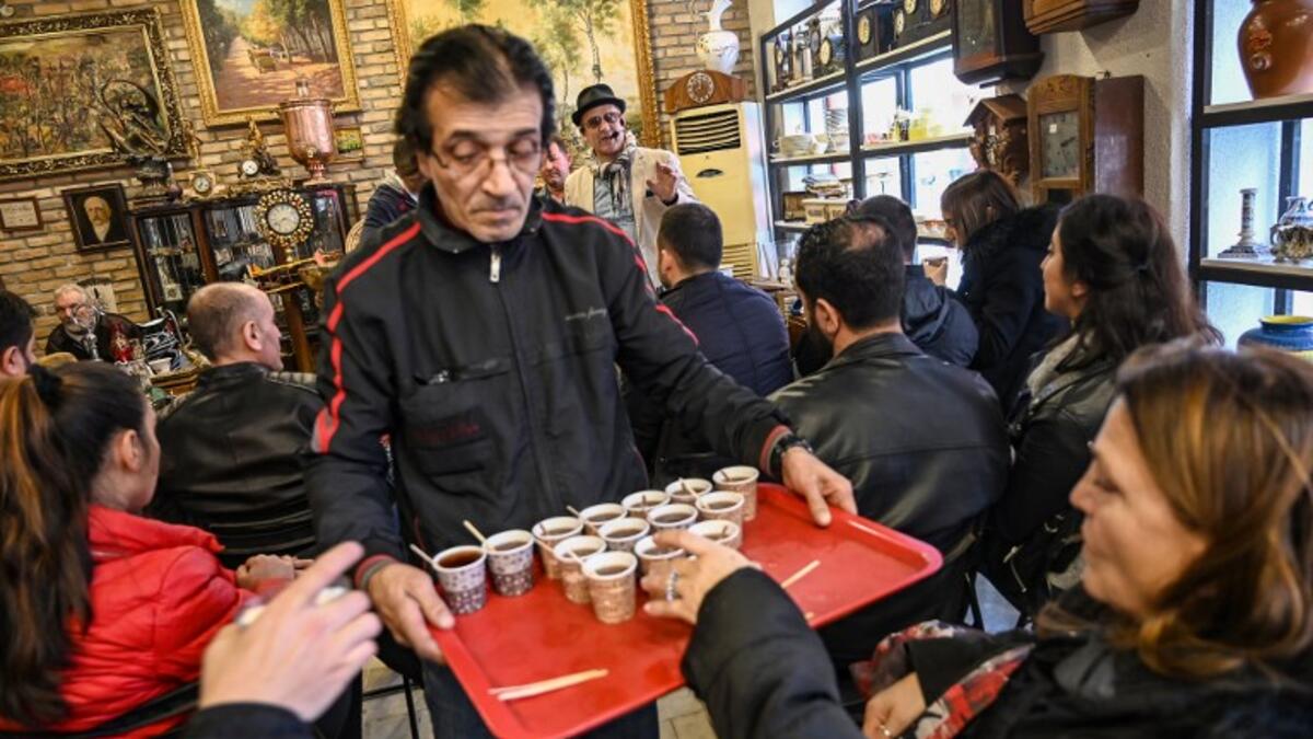 A man serves tea as auctioneer Ali Tuna (back R) shows items to the audience at an auction house in Istanbul's Balat district.
OZAN KOSE / AFP